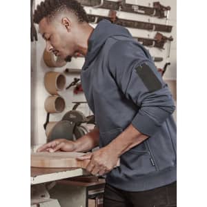 Unisex multi-pocket hoodie in navy, featuring a side pocket, worn by a person working in a workshop.