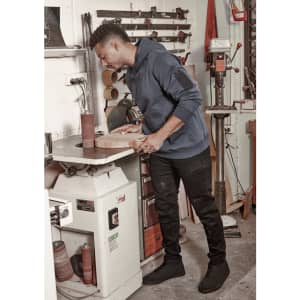 A unisex multi-pocket hoodie in navy, worn by a person working with wood in a workshop setting, alongside various tools.