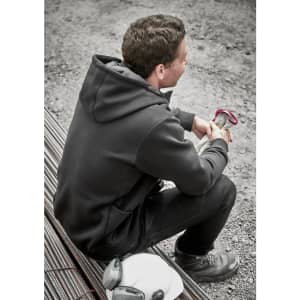 A unisex zip front hoodie in black, featuring multiple pockets, worn by a seated person on a construction site.