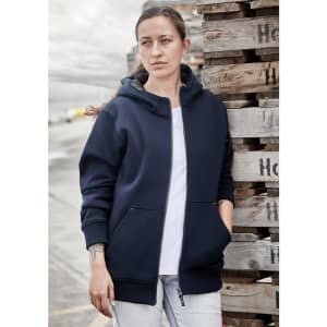 A navy unisex zip front hoodie with multiple pockets, worn by a woman against a backdrop of wooden pallets.