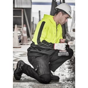 A unisex hi vis full zip hoodie in bright yellow, worn by a person kneeling and working on a construction site.