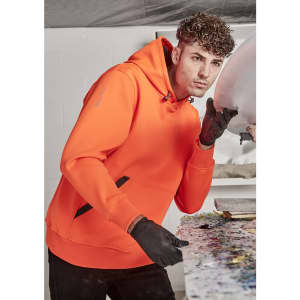 An orange unisex water-resistant hoodie with a black logo, worn by a person in a workshop setting.