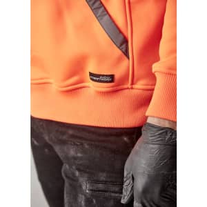 An orange water-resistant hoodie with a logo and a diagonal black detail, paired with black pants and gloved hands.