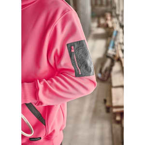 A unisex water-resistant hoodie in pink with a grey zip pocket on the arm, set against a construction background.