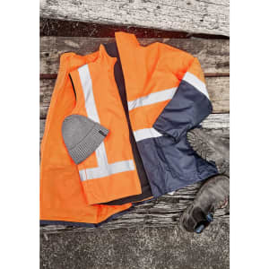 A reversible vest in orange and navy with reflective stripes, paired with a grey beanie and black work boots.