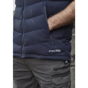 A navy unisex hooded puffer vest with a zip pocket and a logo on the side, worn over grey cargo pants.