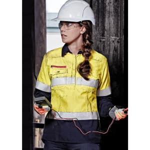 A yellow and navy women's safety shirt with reflective strips, worn with a hard hat and safety glasses.