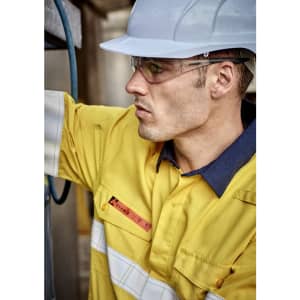A man wearing a yellow work shirt with white reflective strips and a blue collar, accompanied by safety glasses and a hard hat.
