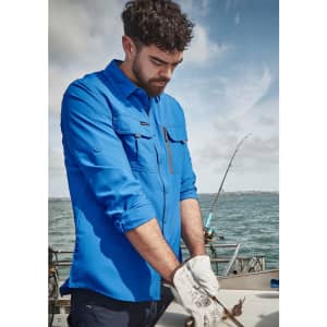 A long sleeve button-up shirt in blue, featuring pockets, worn by a man fishing on a boat.