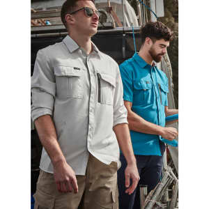 Men wearing long sleeve button-up shirts in light grey and blue, with cargo shorts, standing on a boat.