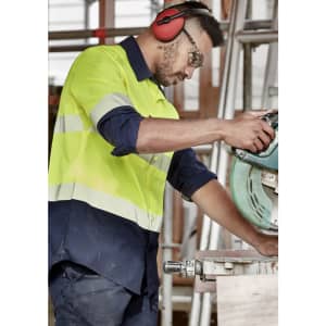 A segmented long sleeve work shirt in hi-vis yellow and navy, featuring reflective tape and a logo, worn by a male worker.
