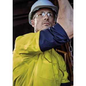 A man wearing a bright yellow long sleeve work shirt with navy blue accents, accompanied by safety glasses and a hard hat.