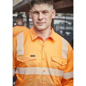 A man wearing an orange work shirt with segmented reflective tape and a logo on the front.