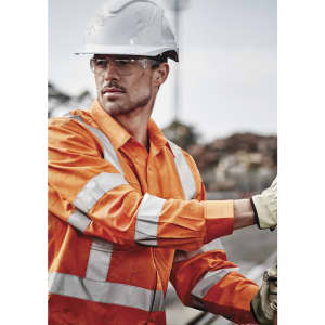 Hi-vis orange long sleeve work shirt with reflective tape, worn by a male worker in a construction setting, wearing safety gear.