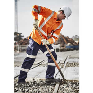 An orange long sleeve work shirt with reflective stripes, worn by a worker using a shovel in a construction environment.