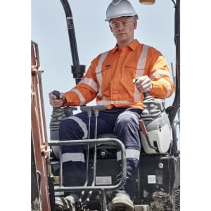 A man operates machinery wearing an orange Hi Vis shirt with segmented tape, alongside navy pants and a white hard hat.