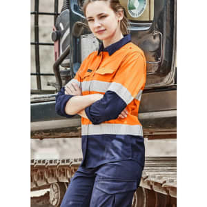 A long sleeve orange and navy work shirt with reflective tape, featuring a logo on the arm, displayed outdoors.