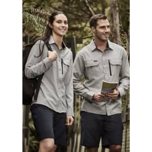 A women's long sleeve button-up shirt in light grey, worn with dark shorts, features a front pocket and branding.