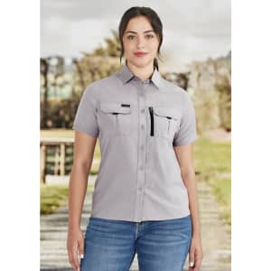A light grey women's outdoor short sleeve shirt with chest pockets and a zipper pocket, featuring a logo.