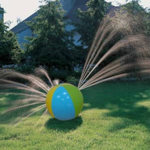 An inflatable water spray ball in blue, green, and yellow, situated on grass with sprays of water emerging from it.