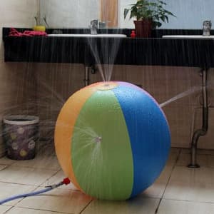 A vibrant inflatable water spray ball featuring orange, green, blue, and yellow sections, spraying water in multiple directions.