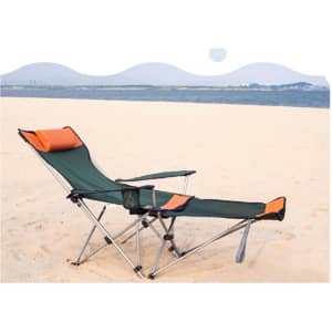 A green and orange camping lounge chair is set up on a sandy beach, facing a calm ocean.