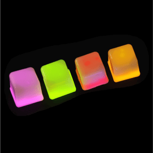 Four brightly coloured light-up ice cubes in pink, green, and orange, emitting a glowing effect against a dark background.