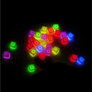 Brightly coloured light-up ice cubes in various shades of pink, green, yellow, and blue scattered against a dark background.