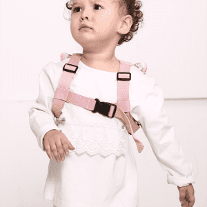 A child wearing pink anti-lost back straps, featuring adjustable clips and decorative details on the shoulders.