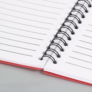 A red spiral notebook with lined pages, featuring black metal spirals and a smooth finish.