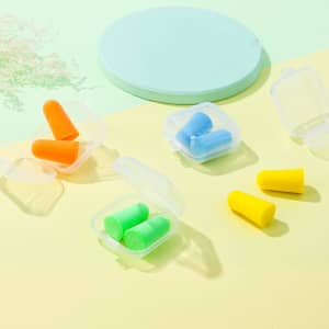 Earplugs in a clear case, featuring orange, green, blue, and yellow earplugs on a light pastel background.