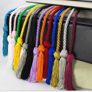 A collection of graduation honour cords in various colours, featuring twisted designs and tassels, displayed over a book.