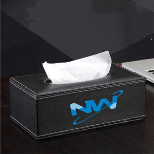 A black leather tissue box with a white tissue emerging from the top. It features a logo on one side.