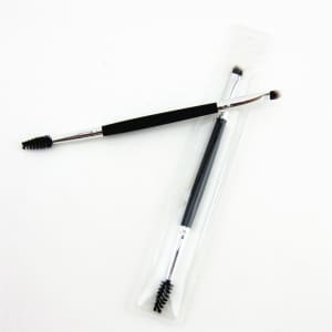 A double-headed eyebrow brush with a black grip, featuring a spoolie on one end and an angled brush on the other, in clear packaging.