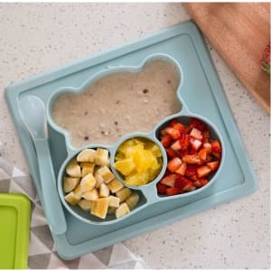 A non-slip children's plate in a bear shape, featuring sections for food in light blue. Includes a spoon.