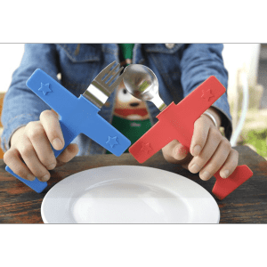 A blue airplane-shaped fork and a red airplane-shaped spoon held above a white plate. The cutlery features star designs.