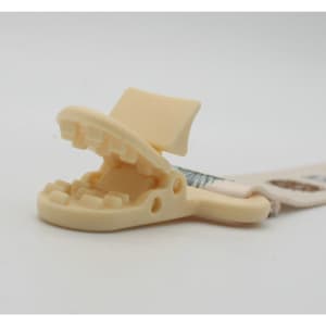 A cream-coloured baby pacifier chain holder with a clip designed to secure pacifiers.