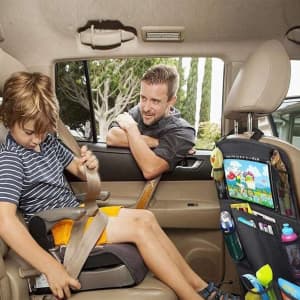 A multi-pocket black car seat organiser bag hangs on the back seat, holding toys, a drink bottle, and a tablet.