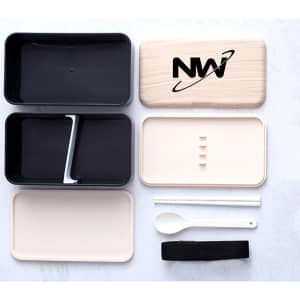 A double-layer lunch box set in black and cream, featuring a spoon, dividers, and a black strap. Includes a logo.