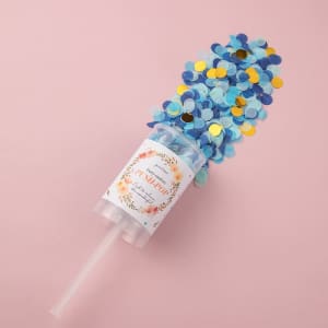 A clear container filled with blue and gold confetti, topped with a plastic straw and a label.