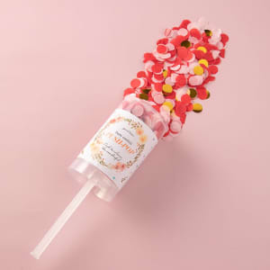 A clear drink bottle filled with red, pink, and yellow confetti, featuring a decorative label and straw.