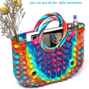 A colourful, multi-hued tote bag featuring raised bubble designs, with handles and contents including books and a drink bottle.