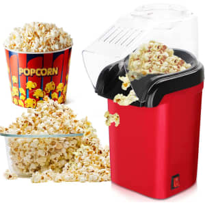 A red hot air popcorn maker with popcorn spilling out, accompanied by a bowl and a striped popcorn container.