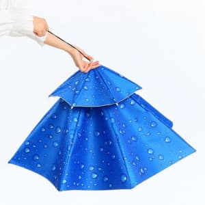A blue folding umbrella with a unique design featuring a water droplet pattern, held by a hand.