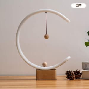 A white magnetic suspension balance lamp with a wooden base and a suspended wooden ball inside a circular design.