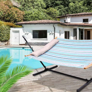 A striped hammock in blue, white, and green fabric displayed by a poolside, featuring a wooden support and a cushion.