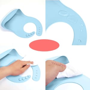 A light blue silicone baby bib with a hand wiping it clean, featuring a logo. Water droplets are visible on the bib.