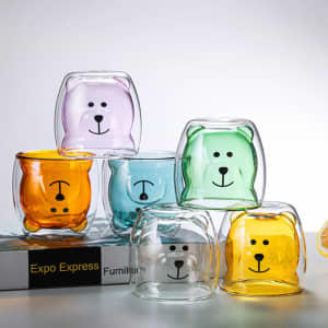 A set of cute bear-shaped glass tumblers in orange, green, purple, and clear glass, featuring playful bear faces.