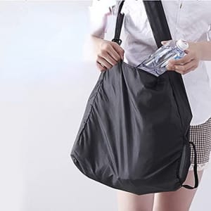 A black folding telescopic storage bag held by a person, with a drink bottle visible inside the bag.
