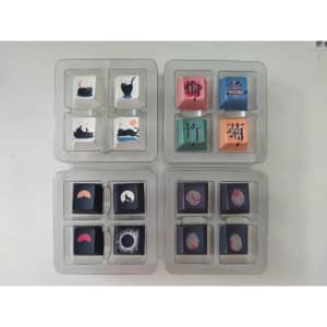 Colourful arrow keycaps arranged in a plastic tray, featuring various artistic designs and colours.